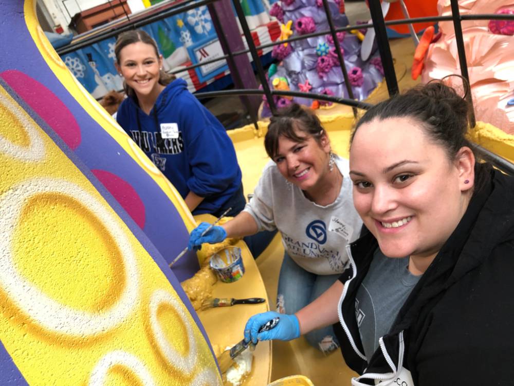 Three women painting a parade float